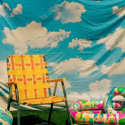 Cover art: a yellow webbed lawn chair and inflatable pool floats in front of the cloud-print backdrop