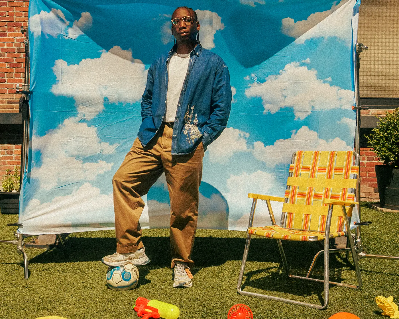 Post Modern Connection member resting a foot on a soccer ball in front of a cloud-print backdrop in a Vancouver backyard
