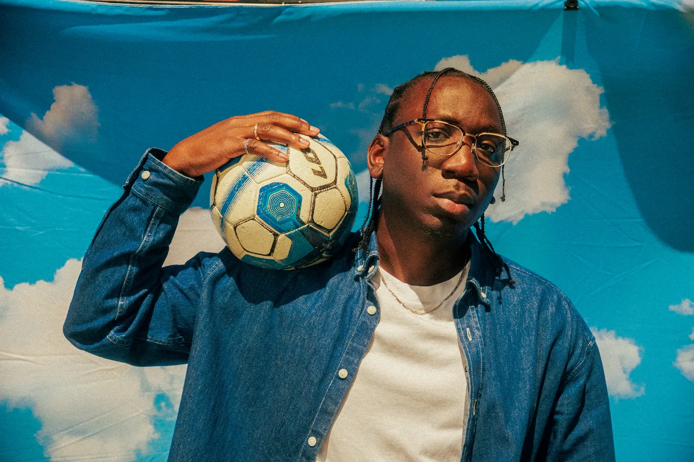 Post Modern Connection member holding a soccer ball in front of a cloud-print backdrop