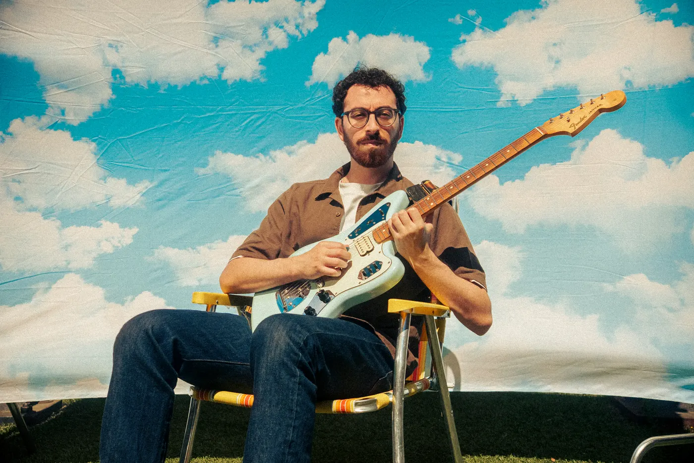 Post Modern Connection guitarist playing in front of a cloud-print backdrop